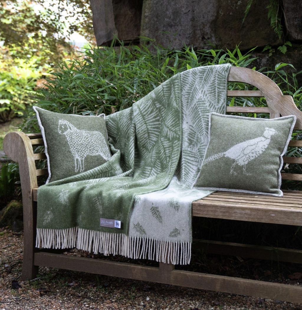 Green fern wool throw and cushion by JJTextile styled on a garden bench, bringing warmth and charm to autumn outdoor living.
