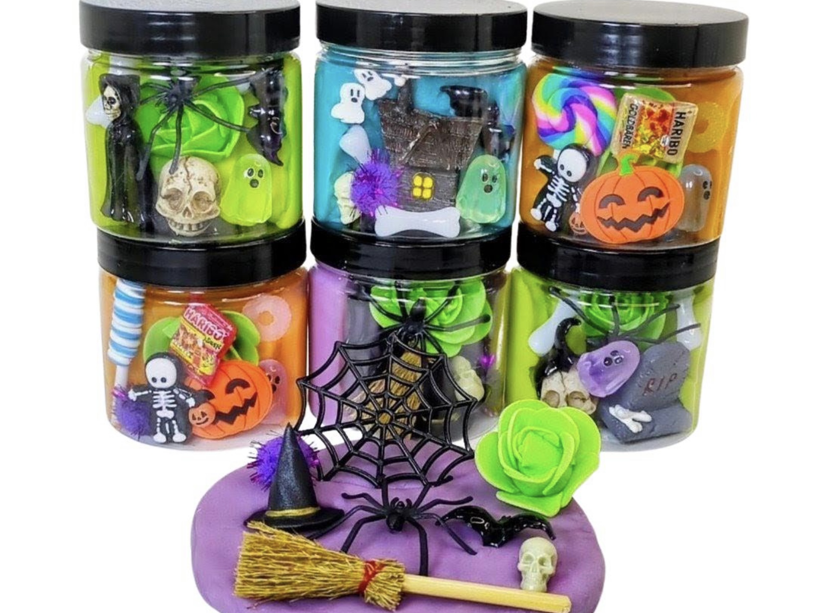 Stacked Halloween play-dough jars with mini charms, cobwebs and pumpkins