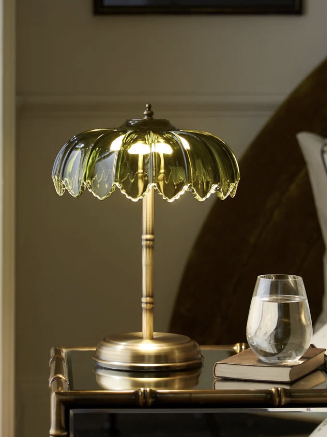 Gold and green scalloped glass table lamp on a black apothecary console 