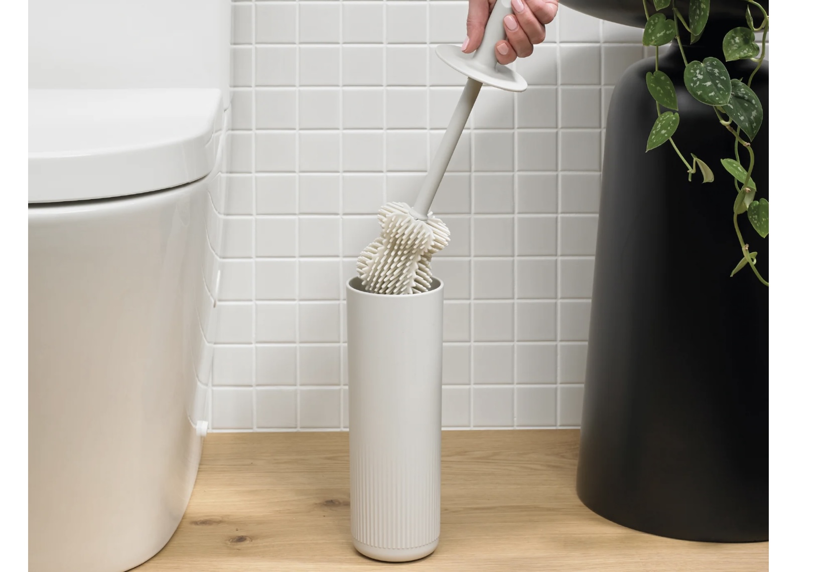 ReBorn recycled plastic toilet brush in matte light grey next to white tiled wall