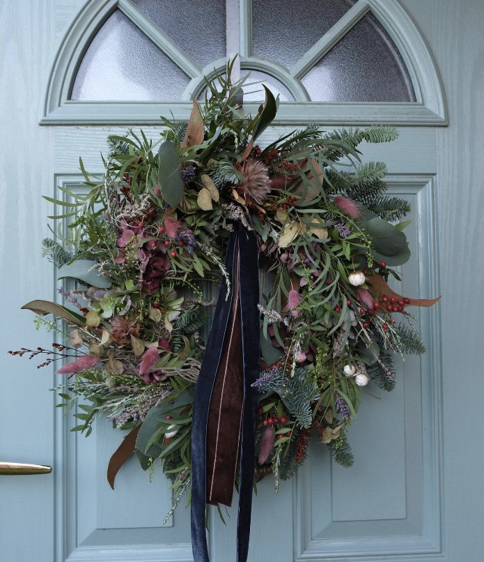 Fresh and dried hydrangea luxury wreath with autumnal foliage and long velvet ribbon on a blue door