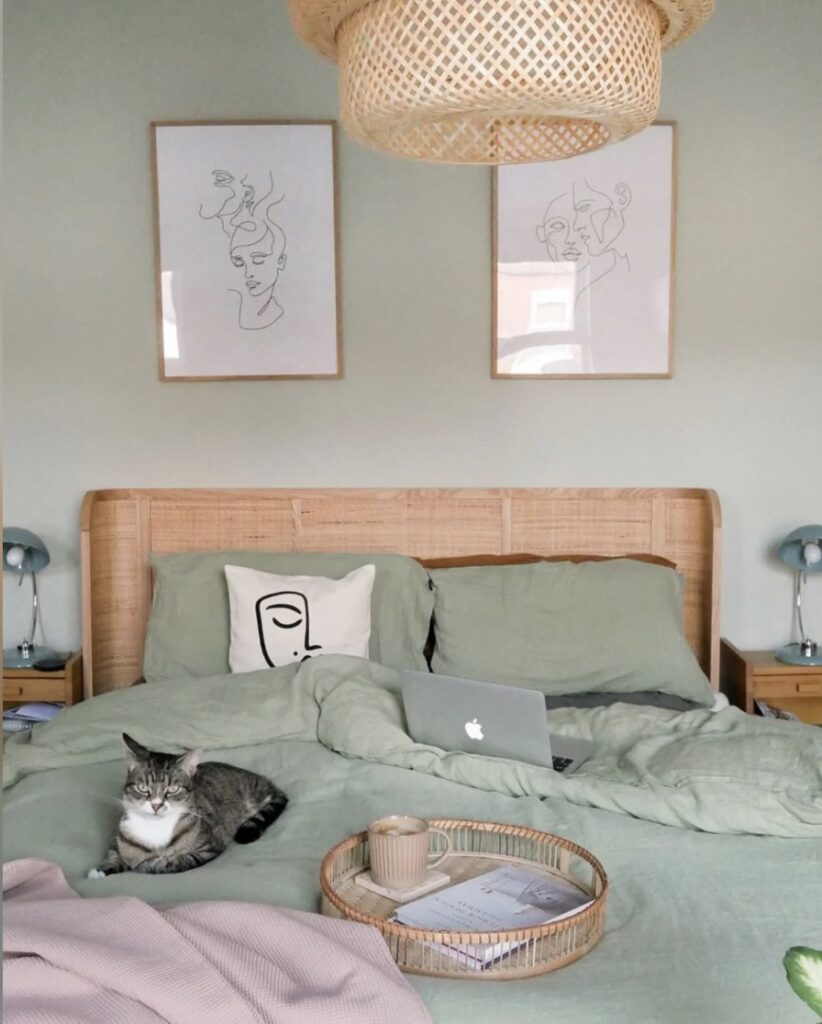 Boho sage green bedroom with Mizzle green walls, rattan headboard and soft green bedding.