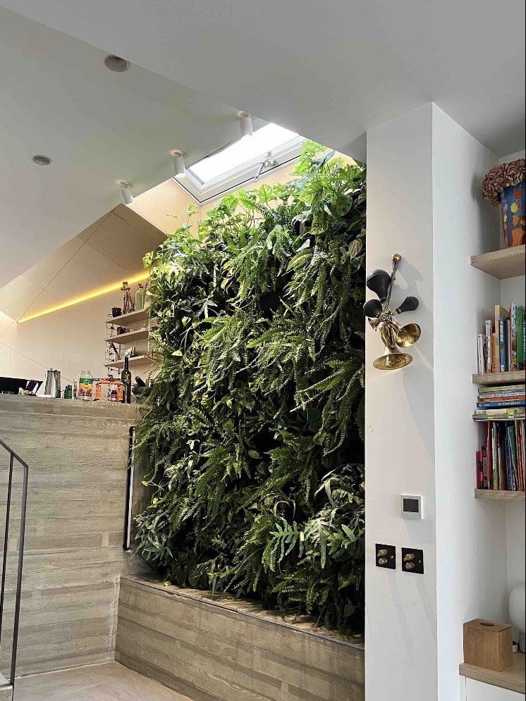 Living wall planter troughs forming a vertical indoor garden wall beside a staircase