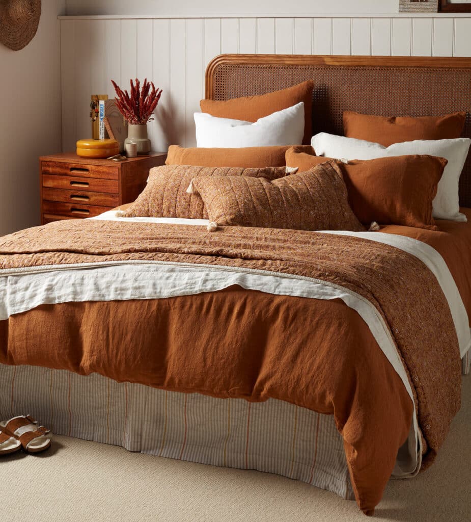 Amber linen duvet cover styled in a modern boho bedroom with rattan headboard and warm neutral bedding