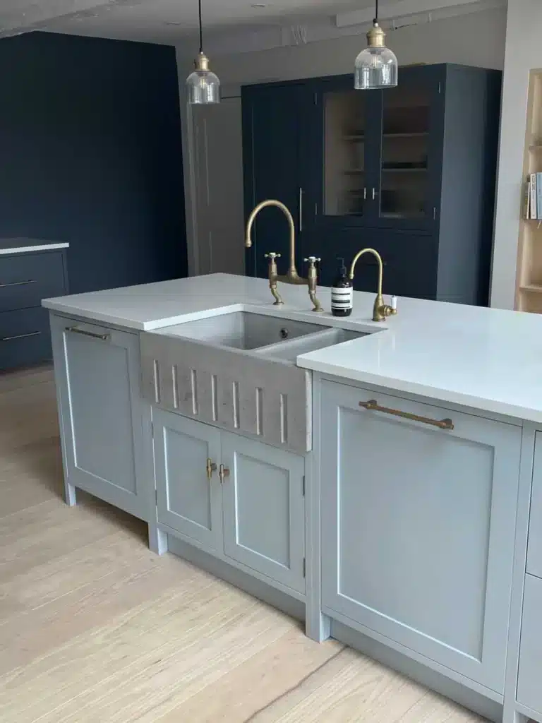 Two tone kitchen with soft blue island, concrete Belfast sink, brass bridge tap and dark navy cabinetry and pantry cupboards.​​​​​​​​​​​​​​​​