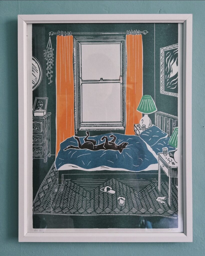 Funny bedroom wall art print of a dog sprawled on an unmade bed, in a white frame