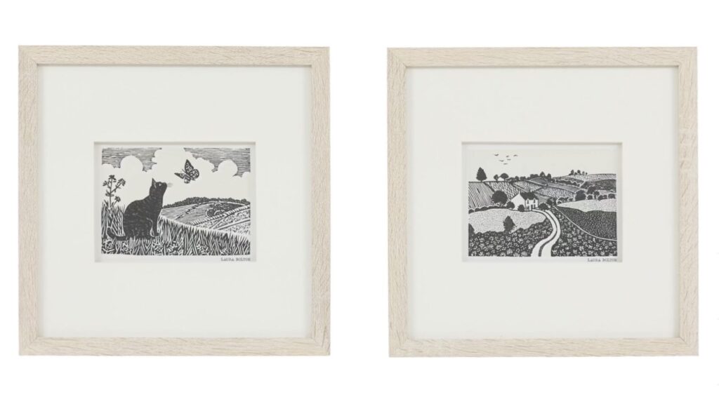 Bedroom wall art prints of a cat and a country lane in pale oak frames with wide white mounts