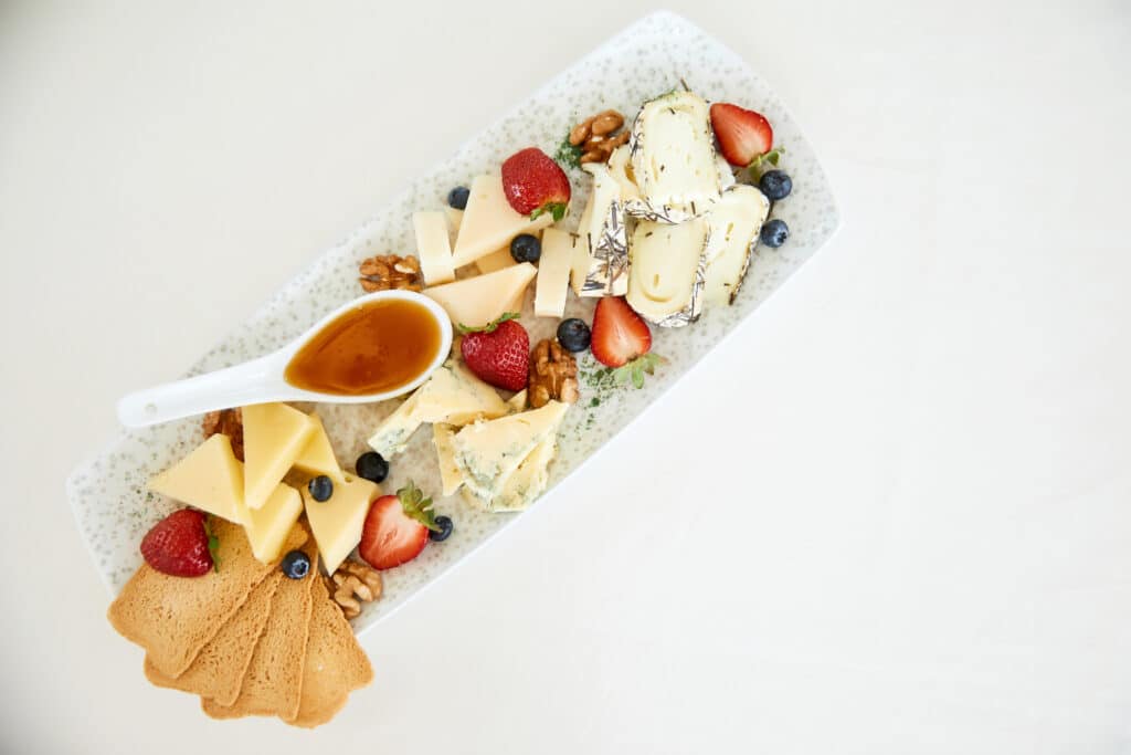Simple cheese plate with honey, walnuts, strawberries and toasts