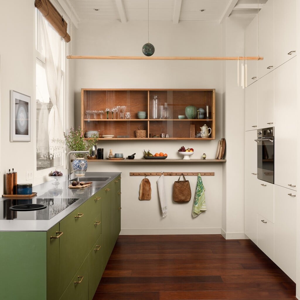 Galley kitchen with base units painted in Bancha, pale tall cabinetry, an open timber wall cabinet, a Shaker peg rail and dark wooden floorboards