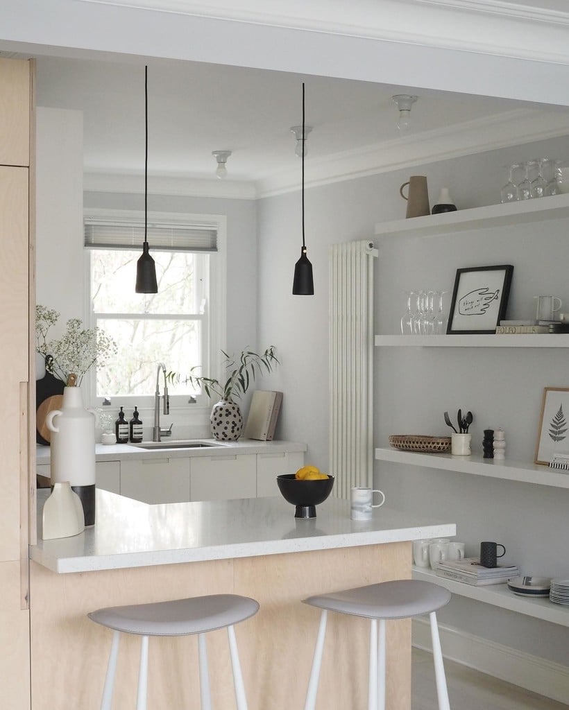 Compact Scandi-style kitchen with walls in Blackened, a birch plywood peninsula, open floating shelves and black pendant lights