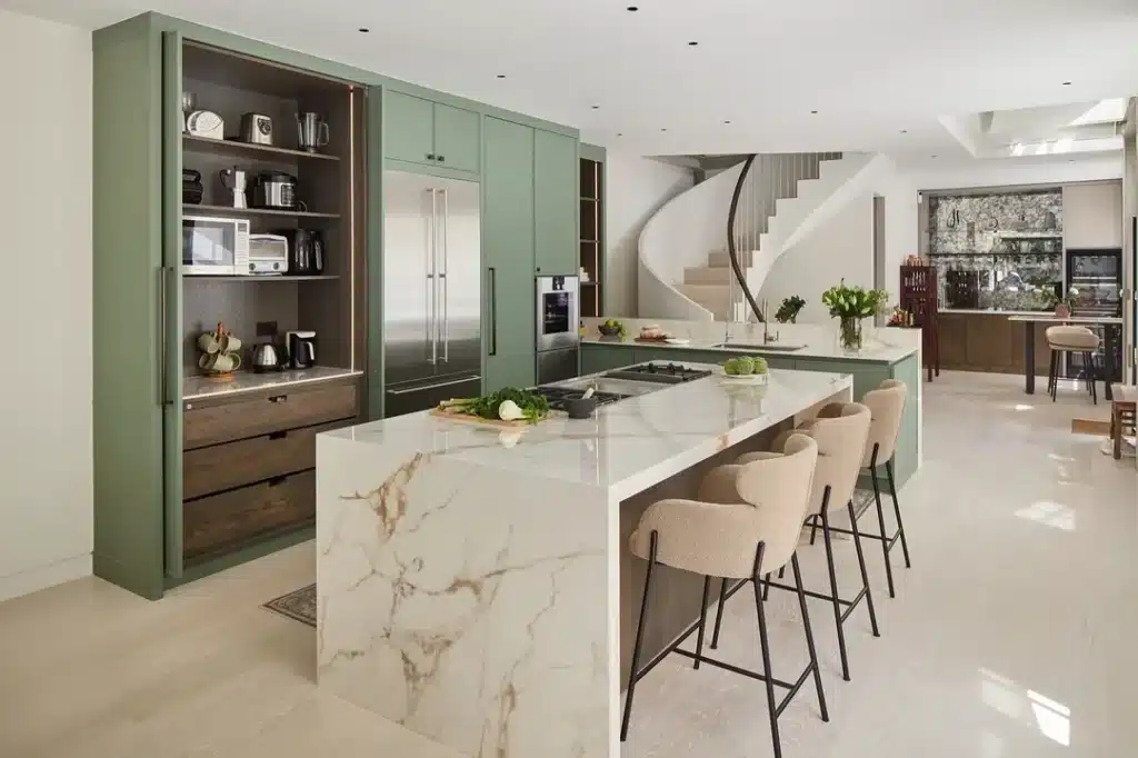 Kitchen renovation with sage green tall cabinetry, marble-effect waterfall island and bouclé bar stools