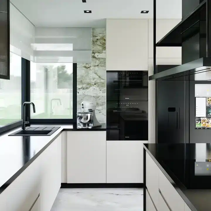 Monochrome kitchen with white handleless units, black worktops, stacked black built-in ovens and a green-veined stone-effect wall panel