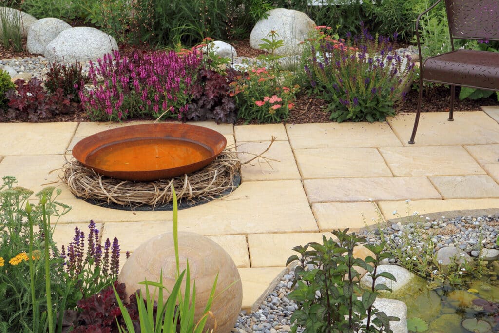 Low maintenance patio garden with gravel edging and a simple water bowl feature