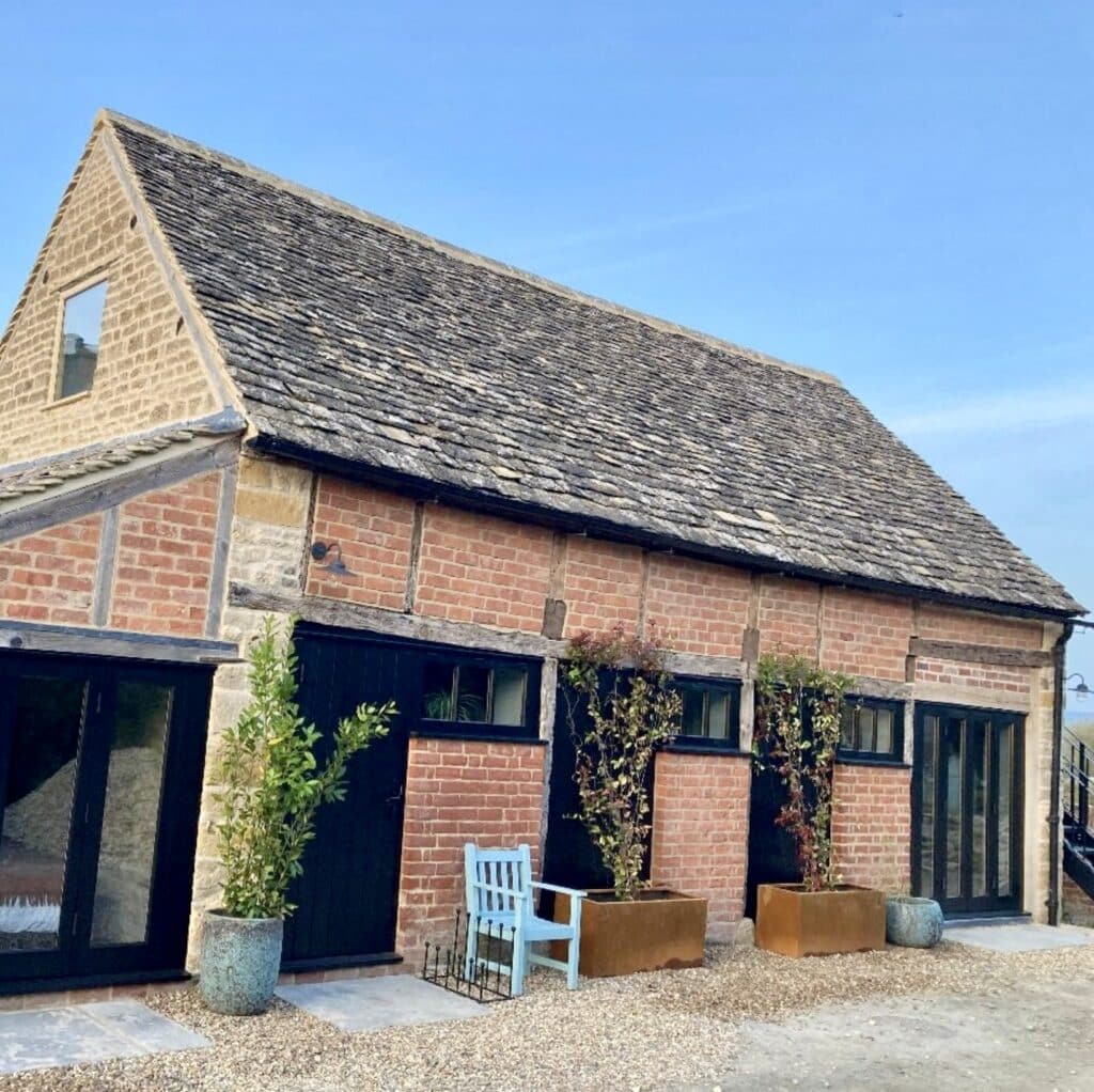 Corten steel trough planters on gravel courtyard outside a modernised barn — a simple, low maintenance garden design with strong structure.