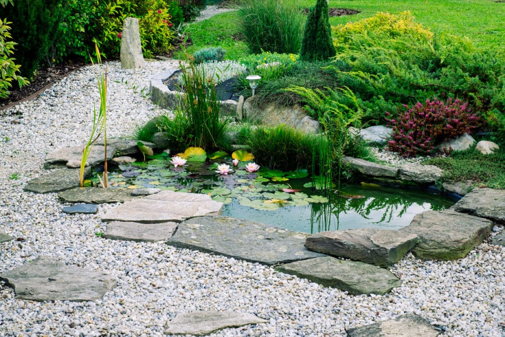 natural garden pond with gravel edging, stone paving and soft planting