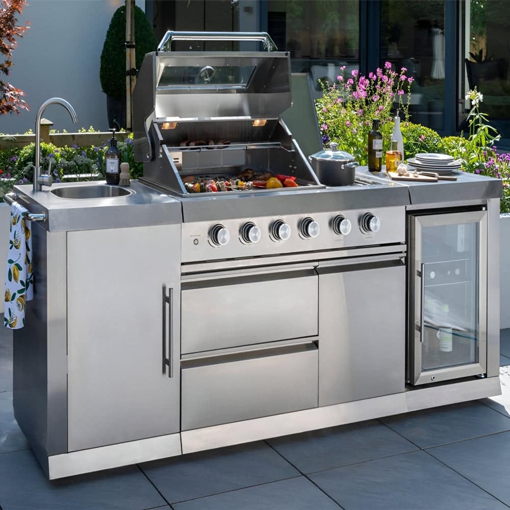 Stainless steel outdoor kitchen with built-in 4-burner gas barbecue, sink and integrated wine cooler on a paved patio