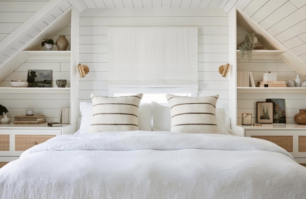 Built-in bedside shelving and panelling under a sloped ceiling in a small bedroom.