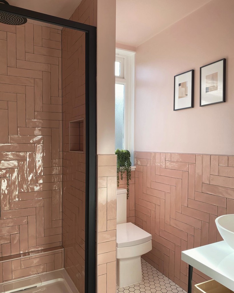 Modern very small bathroom with blush pink herringbone wall tiles, a walk-in shower with black-framed glass, a floating vanity with a vessel sink, and natural light enhancing the soft colour palette.