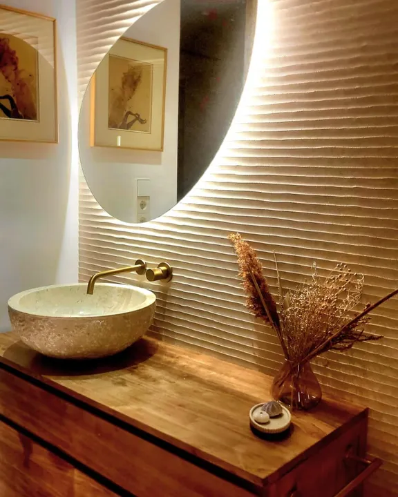 Ribbed textured feature wall with a stone vessel sink, brass tap and wooden vanity