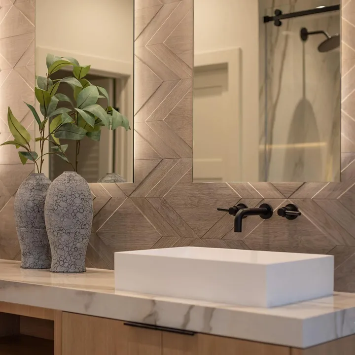 Chevron-relief tile feature wall with a rectangular vessel sink, black fixtures and marble countertop