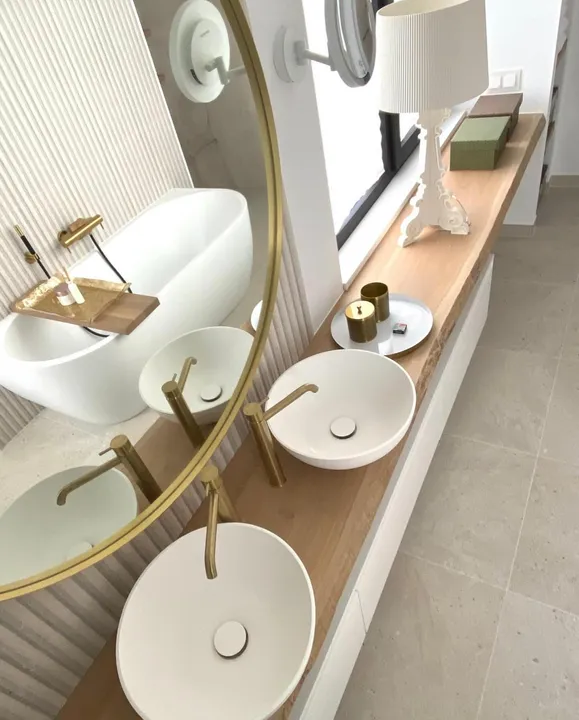Slim live-edge wood shelf with two round vessel basins, brass fixtures and Porcelanosa Spiga Durango ribbed tiling
