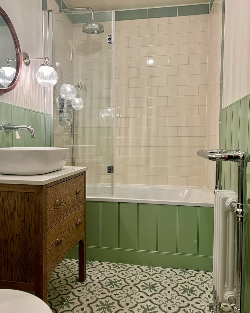 Farrow & Ball Whirlybird green wood panelling with cream subway tile, glass bath screen and patterned floor tiles