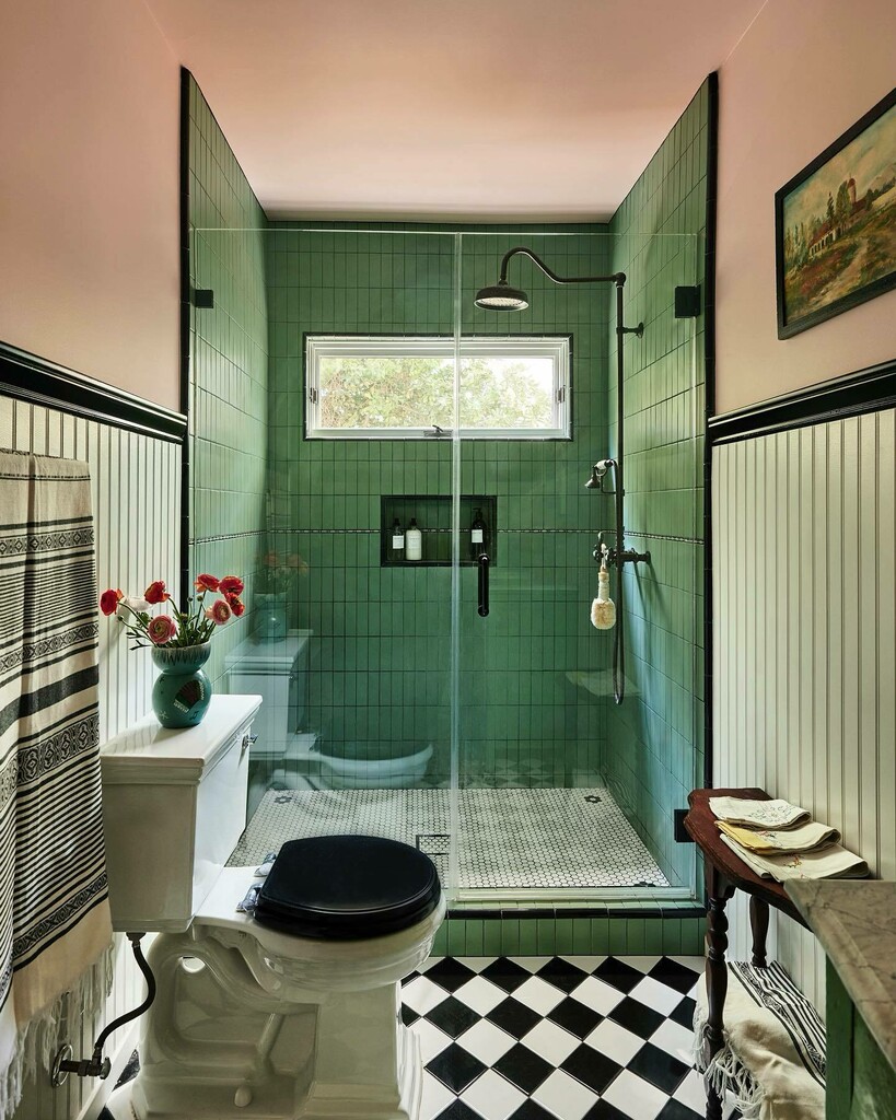 Green tiled walk-in shower with full-height glass screen, black fittings and black-and-white checkerboard floor