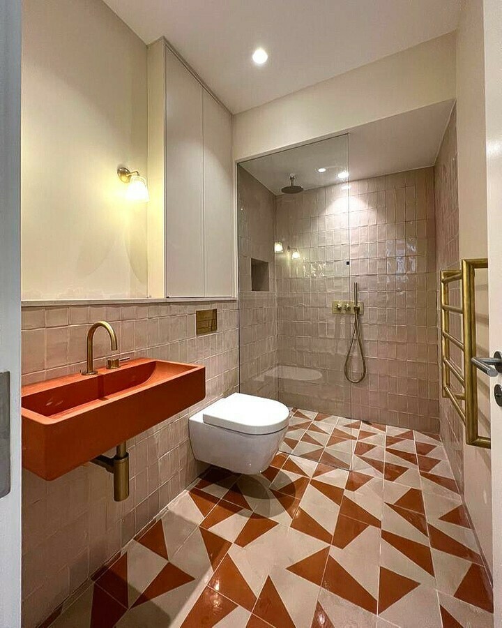 Bathroom with Farrow & Ball Dimity walls, burnt-orange trough sink, brass fixtures and geometric terracotta patterned floor tiles