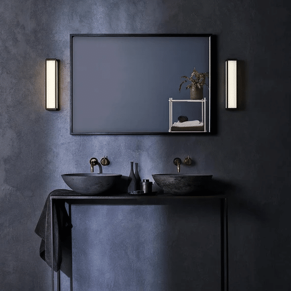 Astro Boston vertical strip wall lights either side of a mirror in a dark blue bathroom