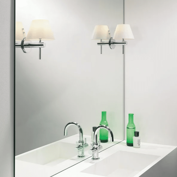 Astro Roma twin sconces with cream fabric shades reflected in a bathroom mirror above chrome taps