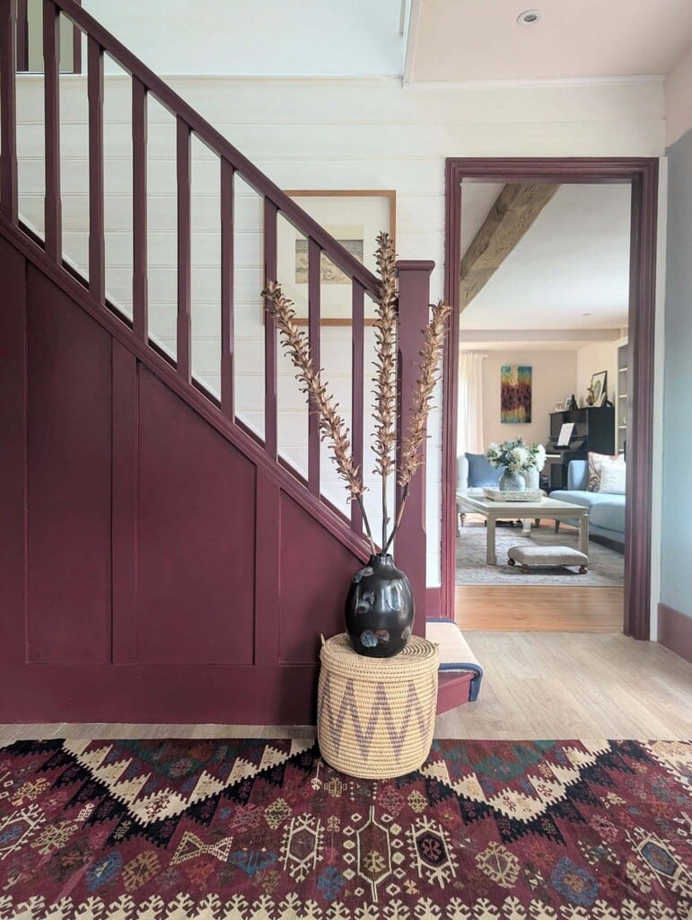 burgundy staircase painted in Farrow and Ball Preference Red with Pointing white panelling and kilim rug