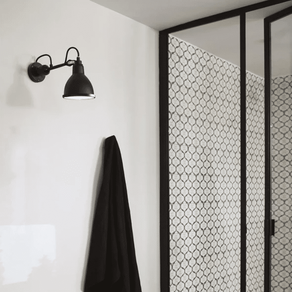 Black adjustable industrial wall light beside a patterned glass shower screen