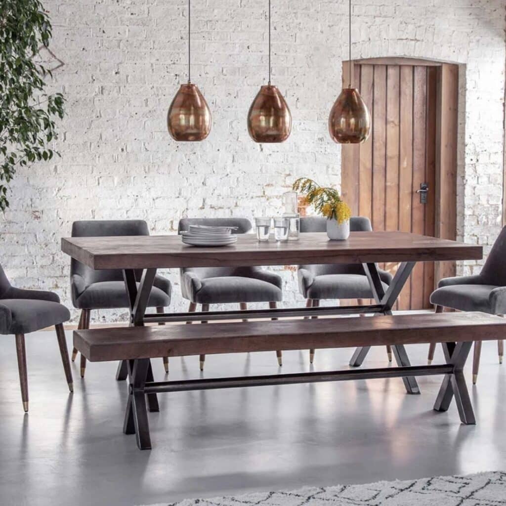 Dining room lighting ideas featuring three pendant lights hung above a rectangular dining table in a rustic industrial dining room