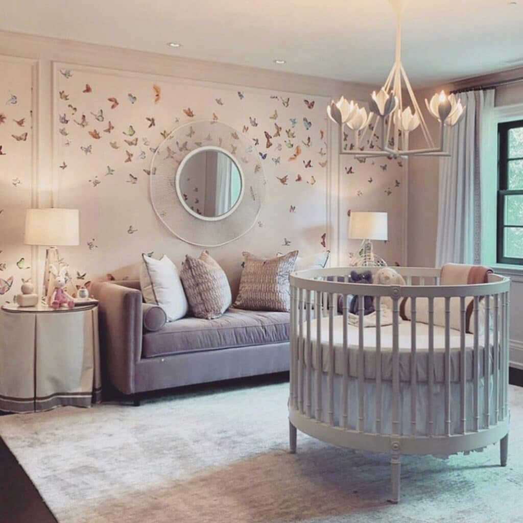 Nursery decor with butterfly chinoiserie wallpaper, round cot and brass mirror