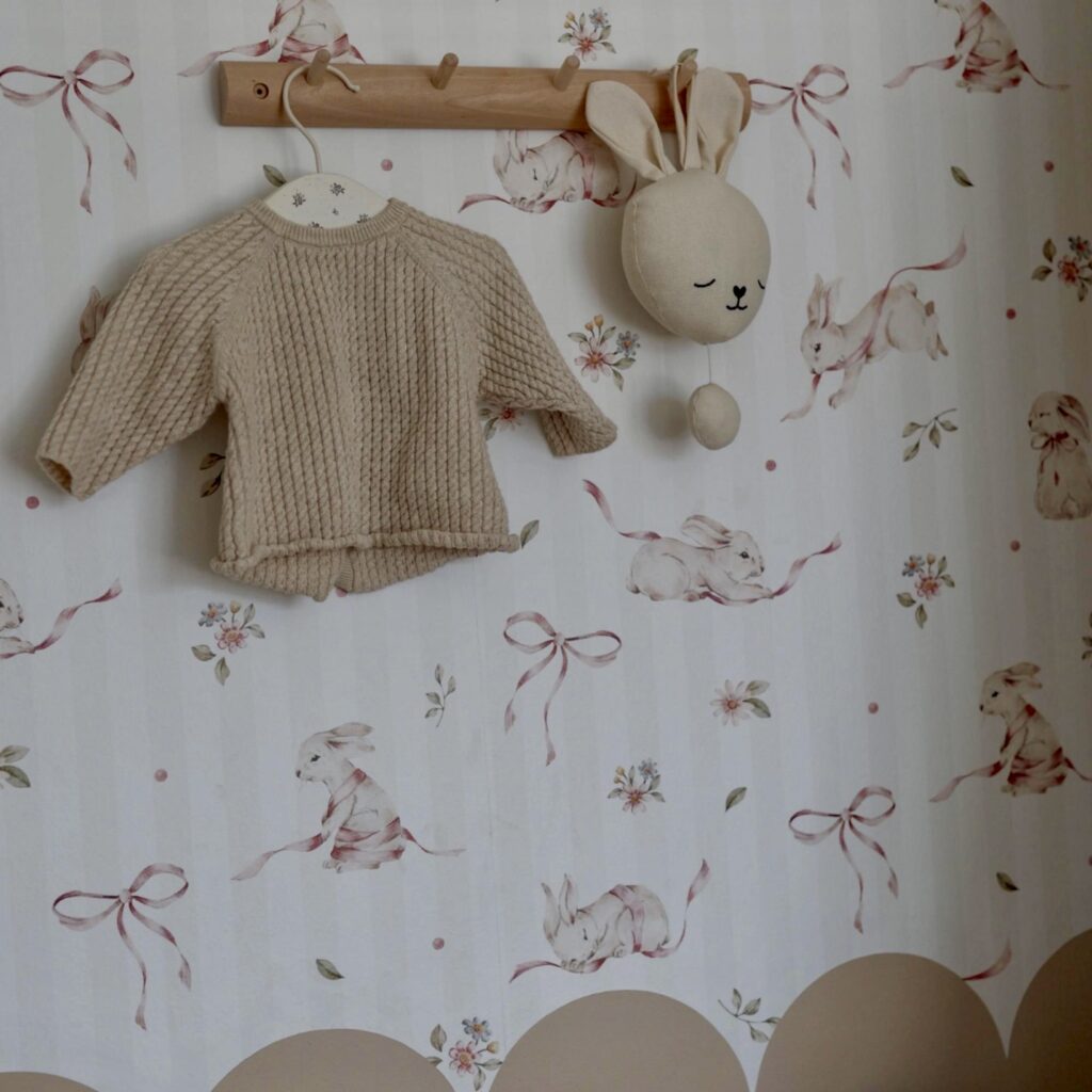 Woodland nursery decor with rabbit wallpaper detail and wooden peg rail