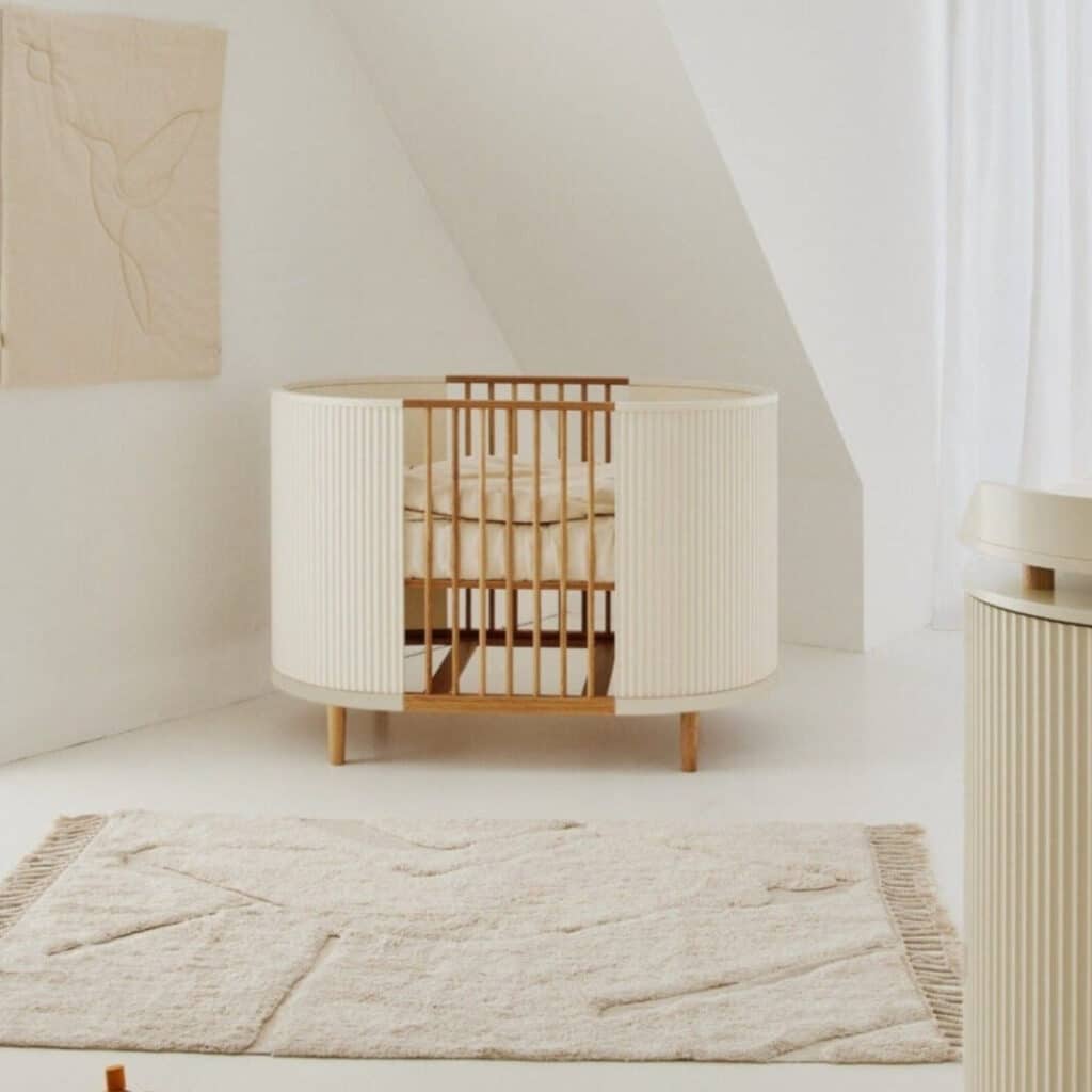 Kas Kopenhagen Kai round cot in cream oak, neutral nursery decor with jute rug and wall hanging