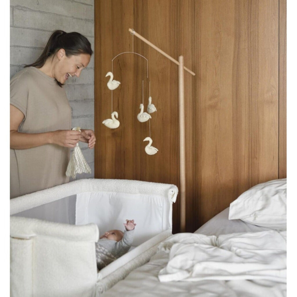 Quax bouclé bedside co-sleeper crib with swan mobile, neutral nursery decor