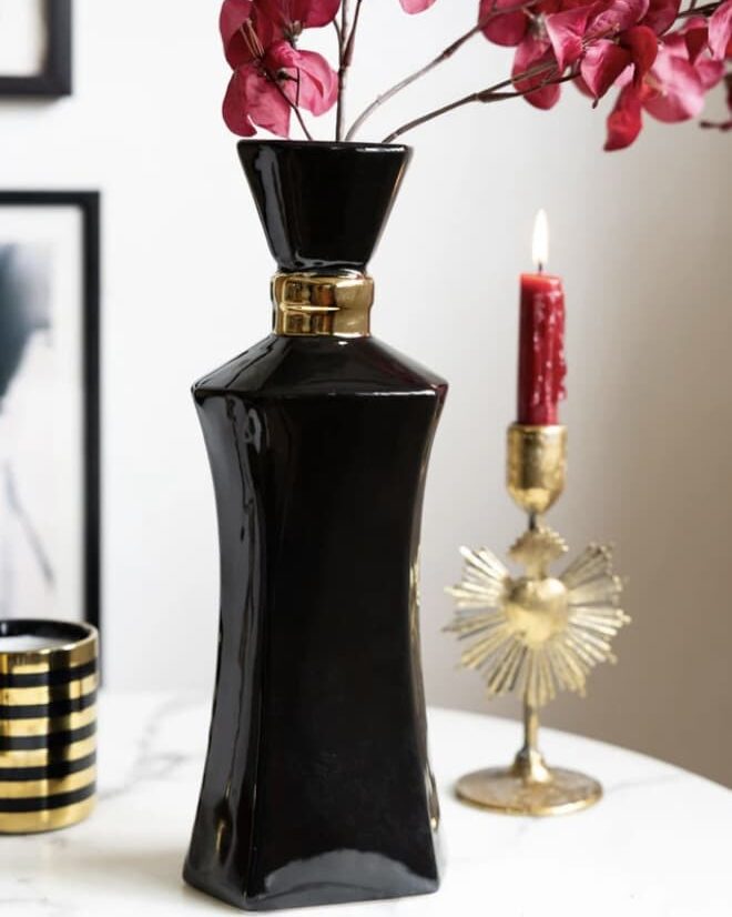 Tall black perfume bottle vase with pink flowers and gold details