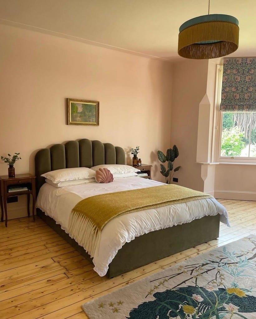 Edwardian bedroom with Farrow & Ball Pink Ground walls, an olive green velvet scalloped bed, mustard throw and patterned Roman blind