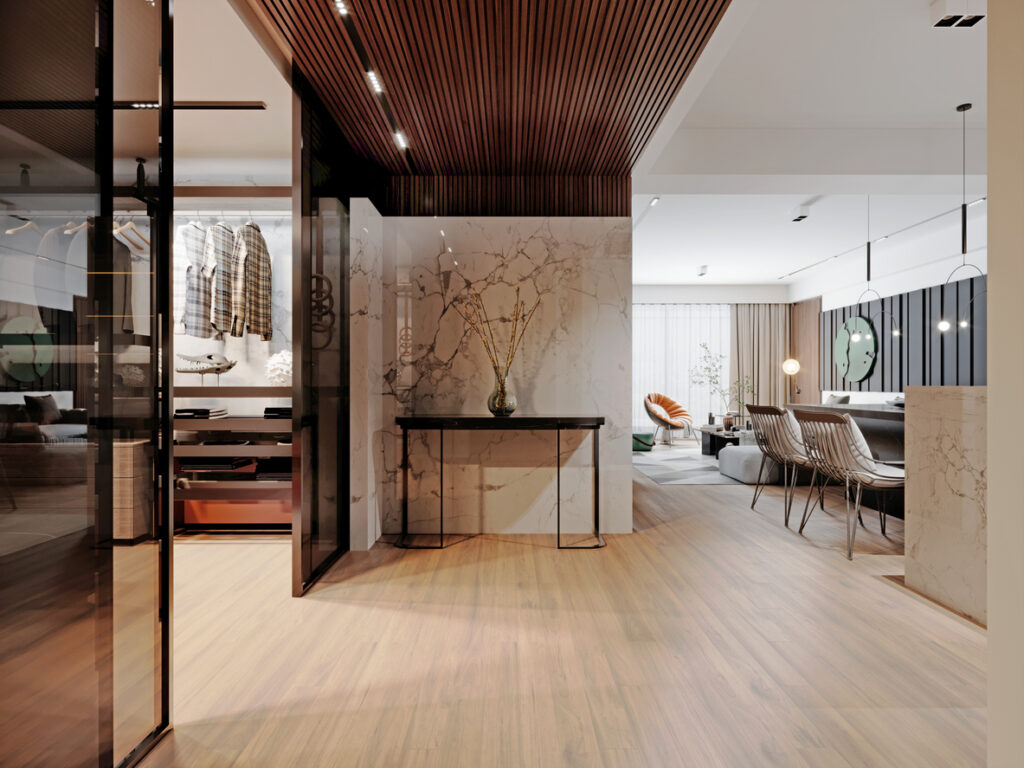Slim black console table against a marble wall panel in a modern open-plan apartment, styled with a single green glass vase with dried branches, wooden slatted ceiling above