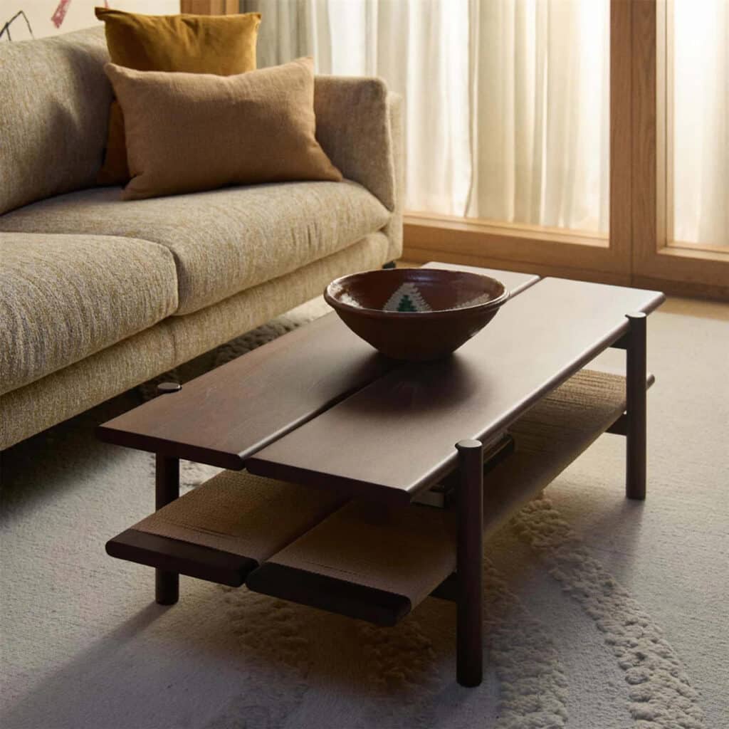 Dark walnut coffee table with a slatted lower shelf and a hand-thrown ceramic bowl in a wabi sabi living room