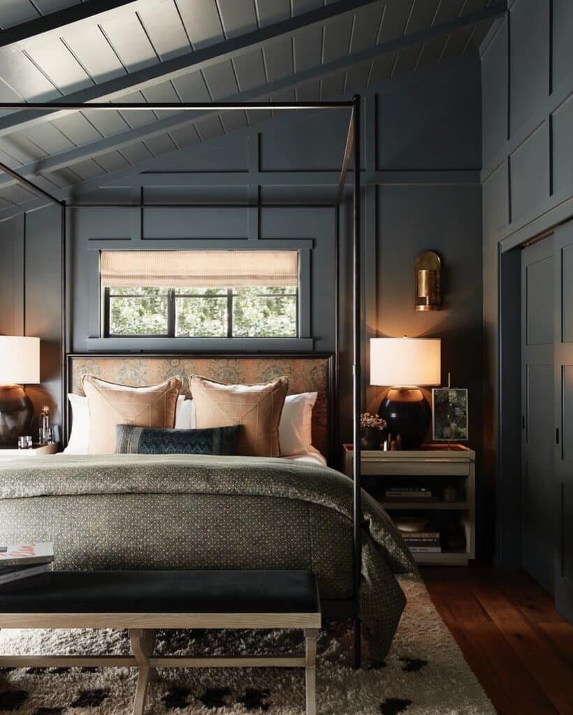 Bedroom with floor-to-ceiling wood wall panelling in Farrow & Ball Inchyra Blue, four poster bed, brass wall lights and layered bedding.