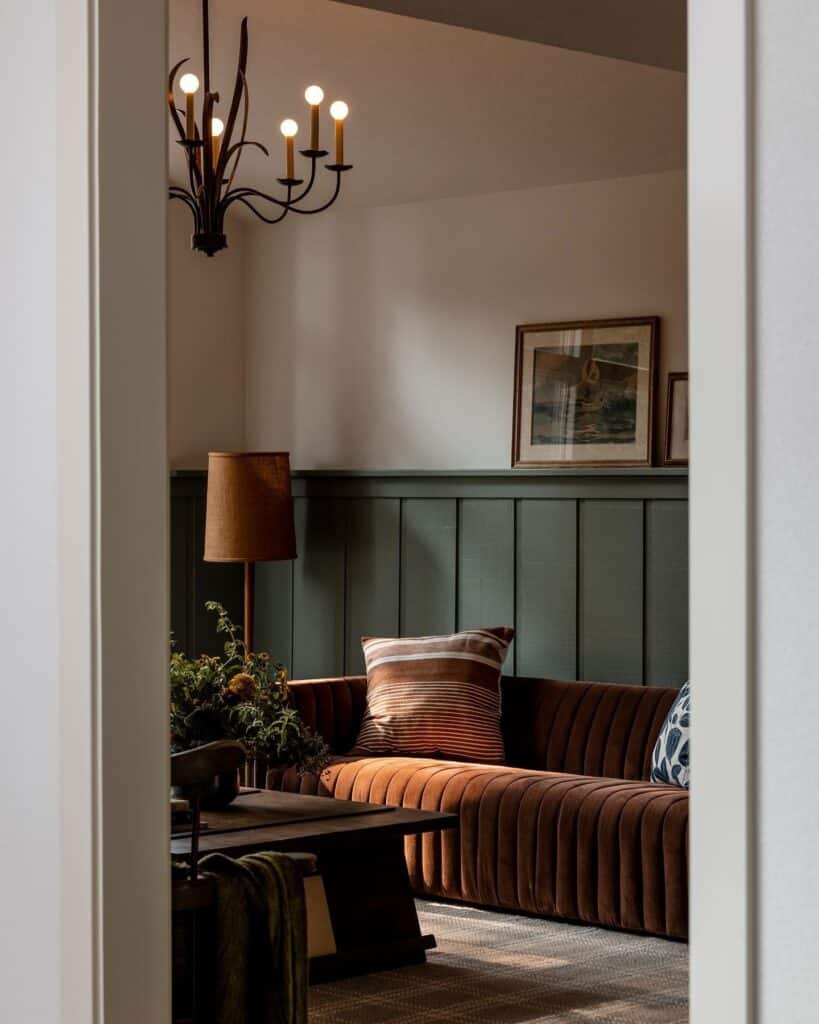 Living room with half-wall Card Room Green wood panelling, rust velvet sofa, bronze chandelier and framed art — Farrow & Ball wall panelling ideas.