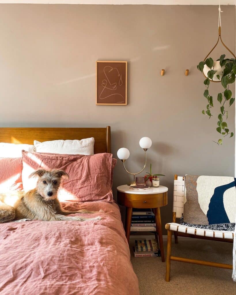 woven accent chair in a bedroom with Farrow and Ball Dove Tale walls and pink linen bedding