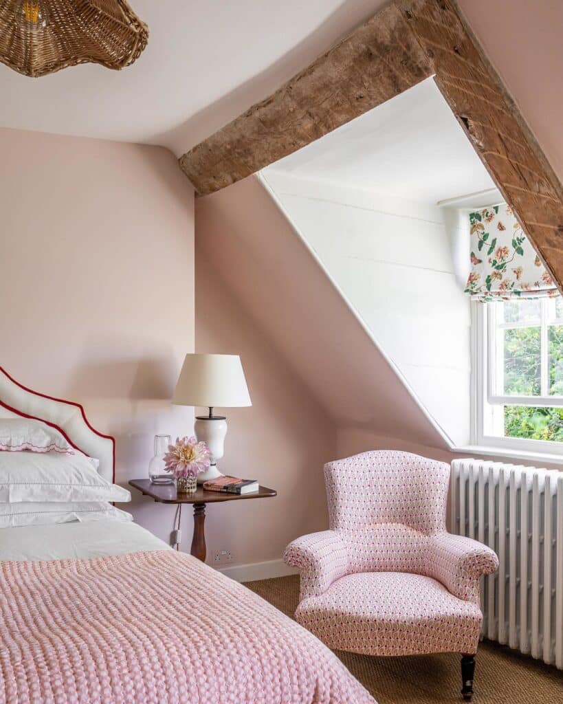 pink textured patterned accent chair against Pink Ground walls in a cottage bedroom with exposed beams