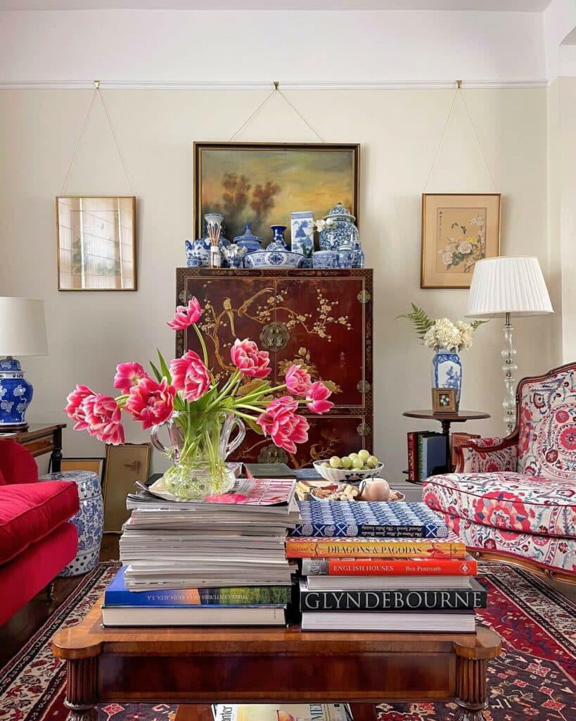 Maximalist living room with red and white floral accent chair, red lacquer cabinet, Persian rug and blue and white ceramics