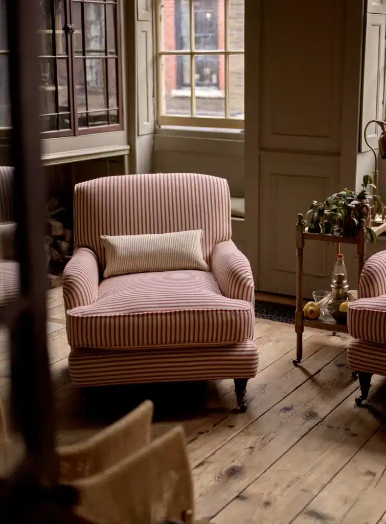 Pair of red and white ticking stripe armchairs beside a window on bare floorboards