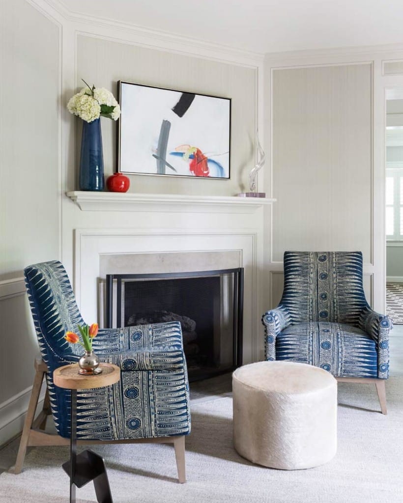 Two matching blue and white print accent chairs styled symmetrically either side of a fireplace in a neutral living room