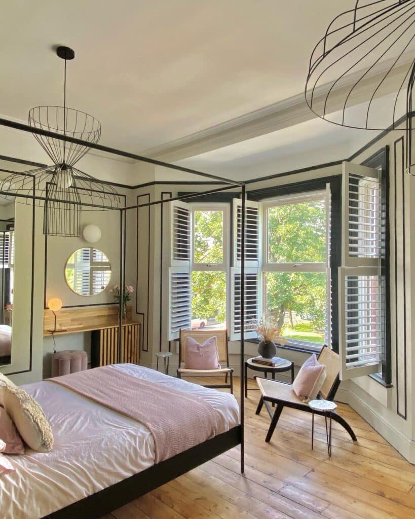 Mid-century rattan shell chair by a bay window in a Purbeck Stone bedroom with graphic pencil-line wall detailing