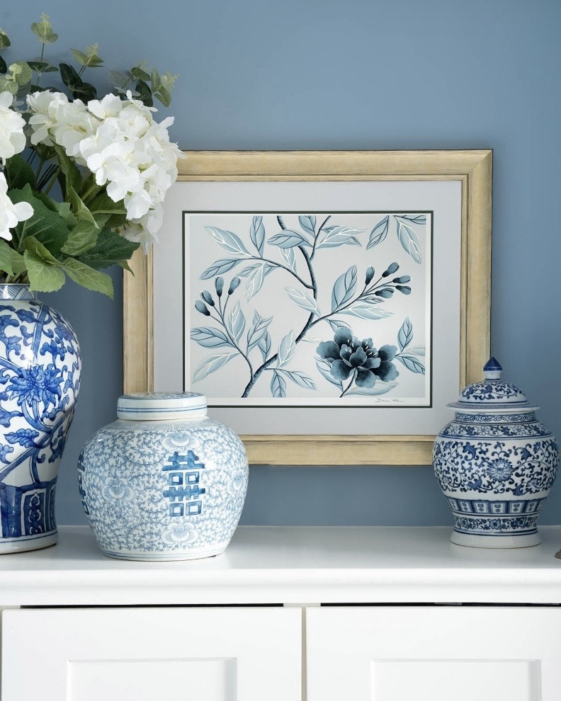 Framed blue and white botanical chinoiserie decor print styled with ginger jars on a console table